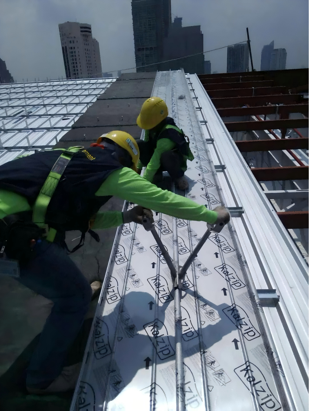 A worker positioning the connection between adjacent roof panels